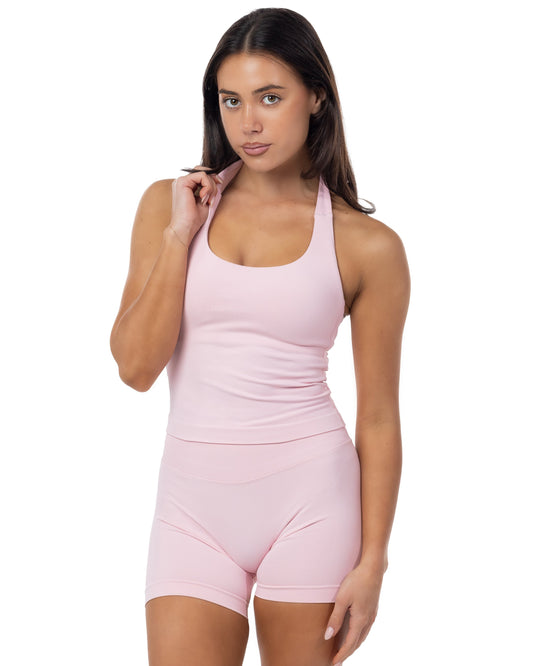 Woman wearing a pink sleeveless top and shorts set on a white background