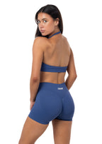 Woman wearing a blue sports bra and shorts set on a white background