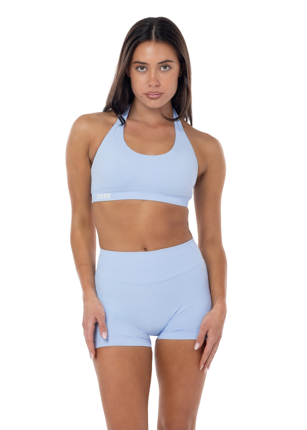 Woman wearing a light blue sports bra and high-waisted shorts on a white background
