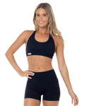 Woman wearing a black sports bra and shorts set on a white background