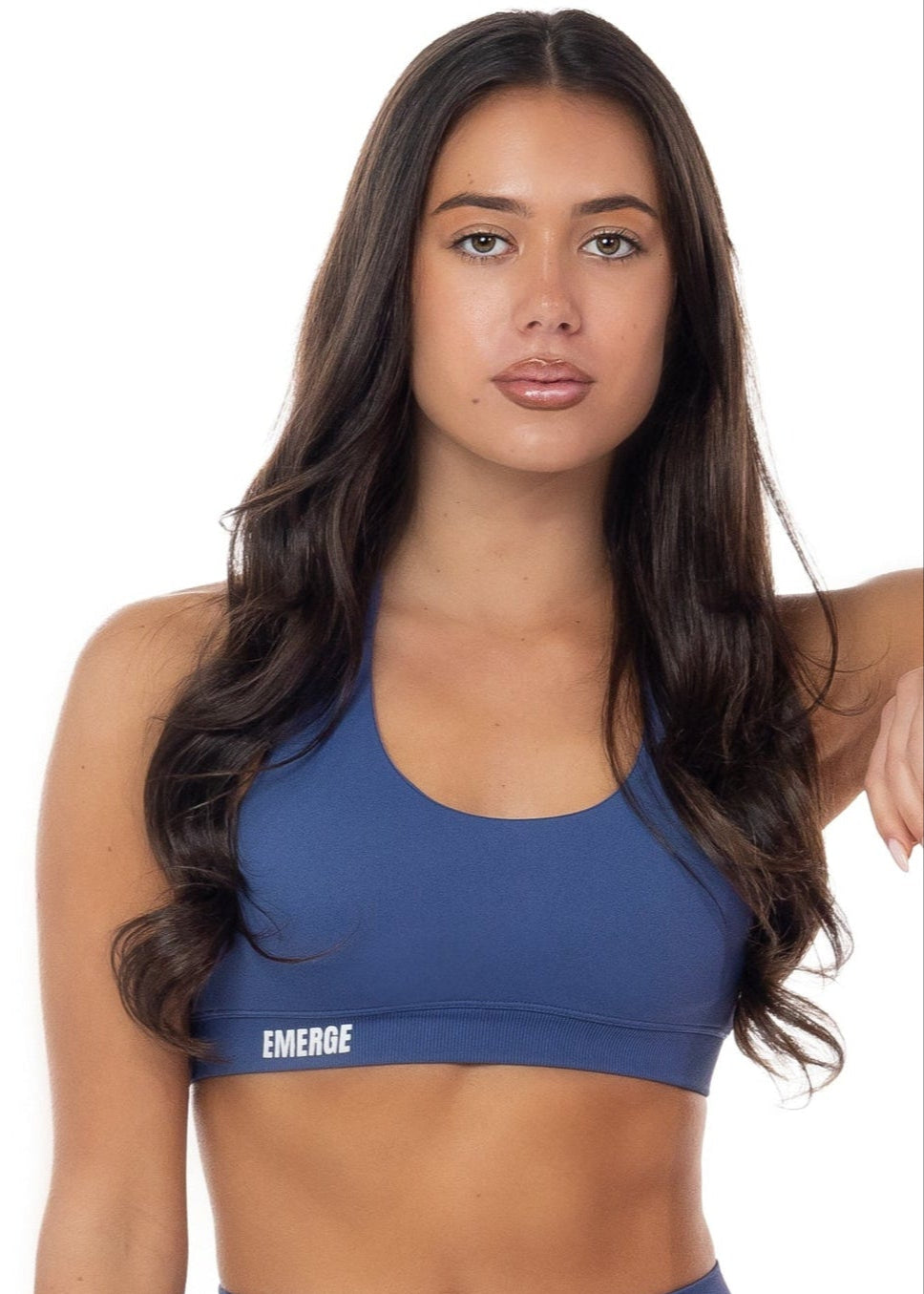 Woman wearing a blue sports bra and shorts with 'EMERGE' branding on a white background